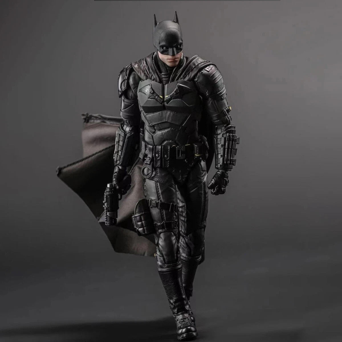 Detailed Batman action figure in black armor suit with cape and utility belt on gray background