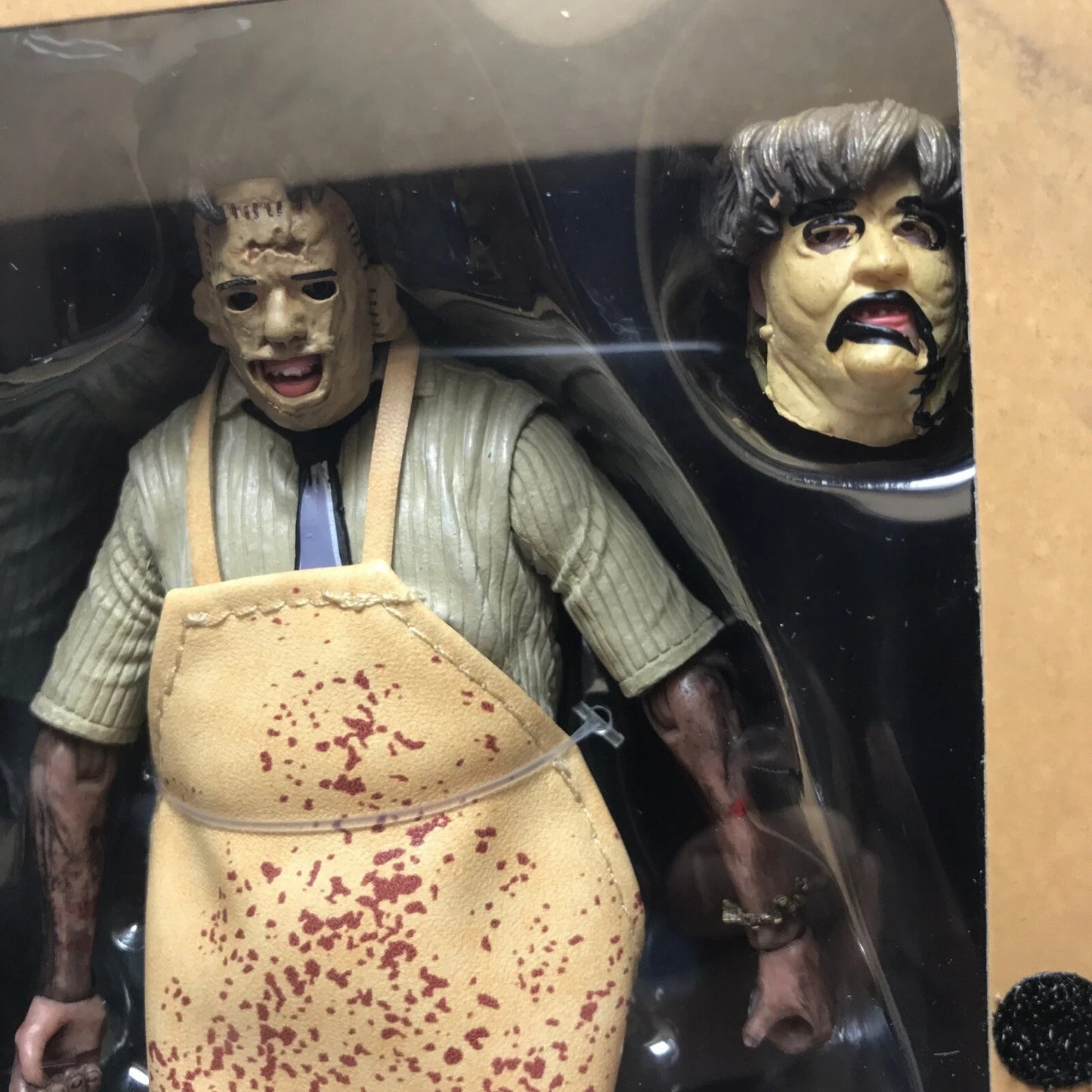 Horror action figure wearing blood-stained apron and stitched mask with alternate unmasked head