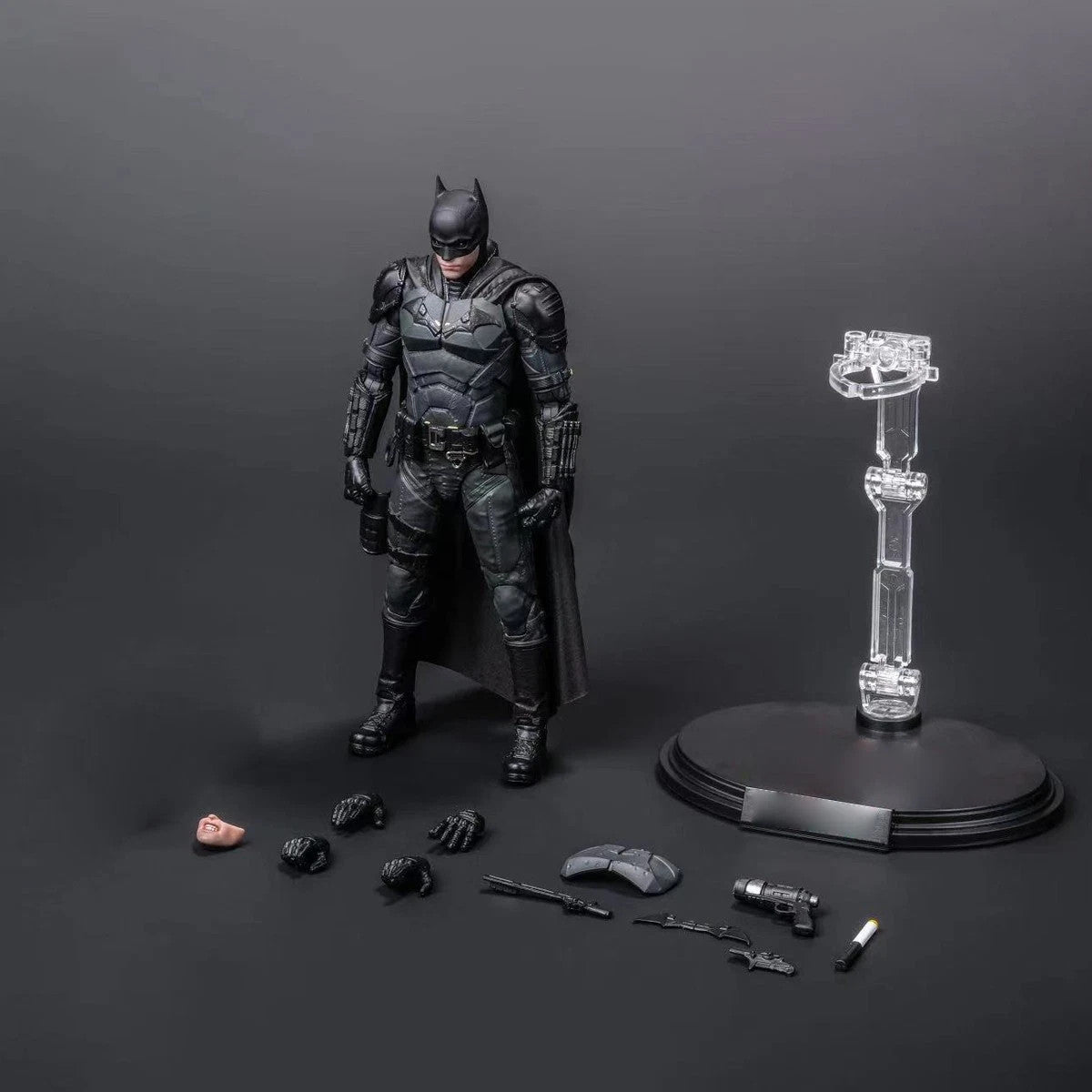 Batman action figure with interchangeable hands, tools, face parts, and display stand on black background