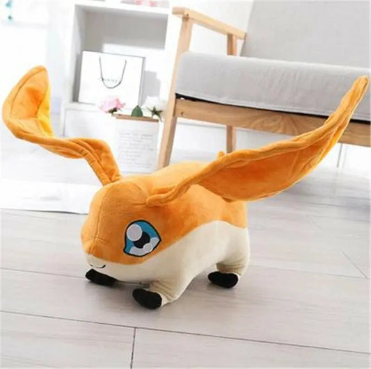 Orange and white plush toy with large ears on wooden floor near grey sofa in bright room