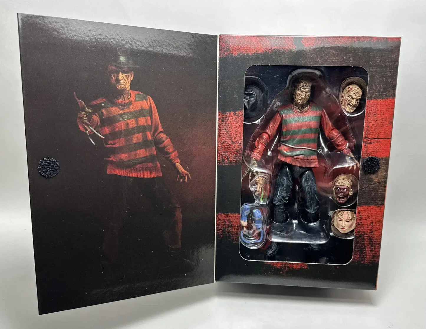 Freddy Krueger horror action figure in black and red striped box with multiple interchangeable heads